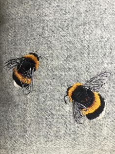 two yellow and black bees sitting on top of a gray sweater