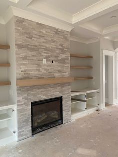 an empty living room with a fireplace and shelves