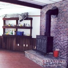 a living room with brick walls and a wood stove in the center, surrounded by shelves