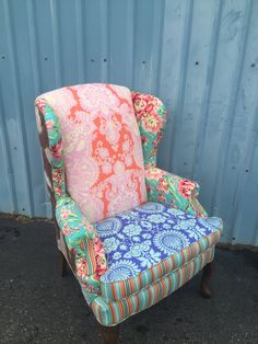 an upholstered chair sitting in front of a blue corrugated wall with flowers on it