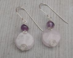 "These are lovely pale pink rose quartz 7/16\"(12mm) round yet flat beads that we topped with 6mm amethyst and some swirly spirals. All the wire is sterling silver including the earwires. The entire earring measures 1 3/8\"(3.5cm) from the very top of the earwire to the very bottom of the earring. The earrings in the photos are not the exact same earrings that you will receive. We choose stones that will look as close as possible to the same ones that are in the pictures.They come from the same Purple Rose Quartz Round Jewelry, Round Purple Rose Quartz Jewelry, Pink Amethyst Round Jewelry, Pink Wire Wrapped Round Earrings, Pink Rose Quartz Round Earrings, Pink Stone Jewelry, Flat Beads, Pale Pink Roses, Rose Quartz Earrings