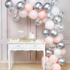 the balloon arch is decorated with silver, pink and white balloons