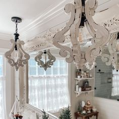 a chandelier hanging from the ceiling in a room with white walls and windows