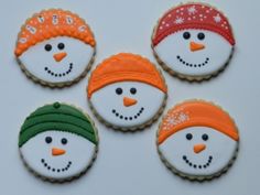 four decorated cookies with frosting on them in the shape of snowmen and hats