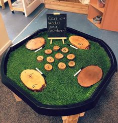 a display in the shape of a golf course with wooden discs and tees on grass