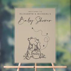 a baby shower sign with a winnie the pooh bear holding a teddy bear on it's back