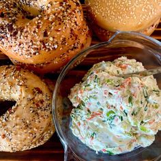 several bagels and dip in bowls on a wooden table