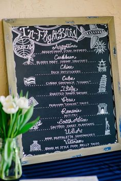 a chalkboard menu on a table with flowers in a vase