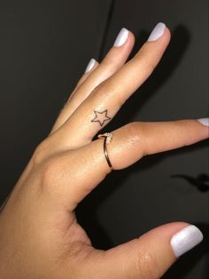 a woman's hand with a star tattoo on her left thumb and a ring in the middle