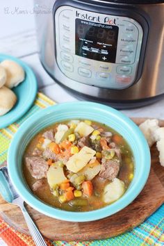 a bowl of stew with potatoes and carrots in front of an instant pot