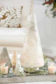 a white christmas tree sitting on top of a table next to candles and other decorations