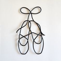 a piece of art that looks like a pair of scissors on a white wall with black string