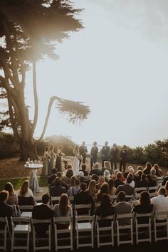 a group of people that are standing in front of some chairs on the grass and trees