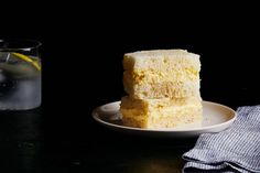 two pieces of cake on a plate next to a glass of water and a napkin