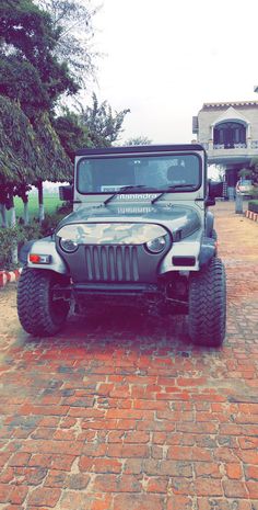 a gray jeep parked on top of a brick road