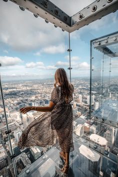 a woman standing on the edge of a high rise looking down at cityscape