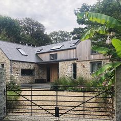 a stone house with a black iron fence and gated in area next to it