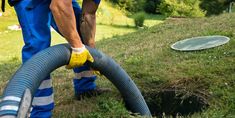 a man is using a vacuum to clean the hole in the grass with a hose