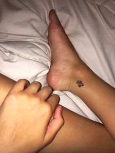 a person laying on top of a bed with a tattoo on their leg and foot