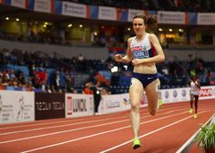 a woman running on a track in front of an audience