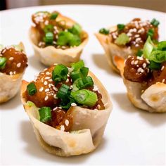 small appetizers with meat and green onions on a white plate, ready to be eaten