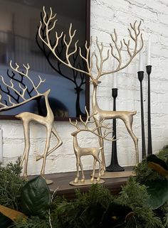 two deer statues sitting next to each other on top of a shelf in front of a window