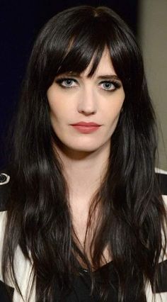 a woman with long black hair and blue eyes is looking at the camera while wearing a striped shirt