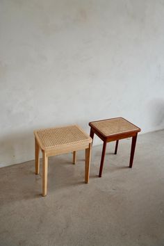 two wooden tables sitting next to each other on cement floored area with wall in background