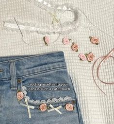 a pair of jeans with pink roses on them next to a white lace bralet