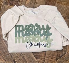 a white sweatshirt that says merry merry christmas on the front and green lettering on the back