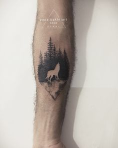 a man's arm with a wolf tattoo on it and trees in the background