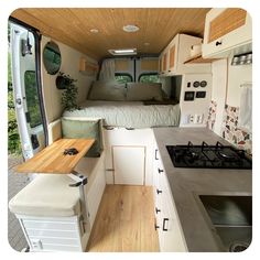 the interior of a camper van with wood flooring and white cabinets, including a bed