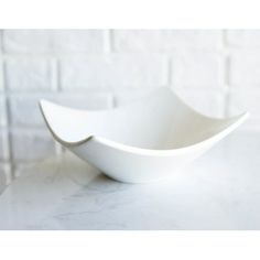 a large white bowl sitting on top of a marble counter next to a brick wall