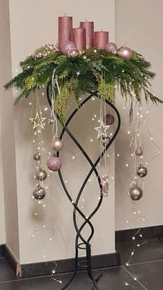 a christmas tree with candles and ornaments on it's stand in front of a wall