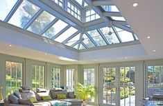 a living room filled with lots of furniture under a glass roof over looking a garden