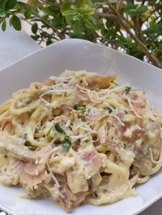 a white bowl filled with pasta and meat covered in cheese on top of a table