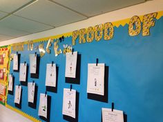 a bulletin board with notes pinned to it in front of a blue wall that says proud o'clock