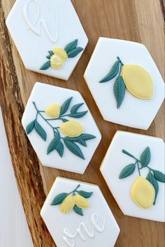 four decorated cookies with lemons and leaves on them sitting on a cutting board next to the word love