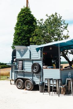 a food truck parked on the side of a road with tables and stools in front of it