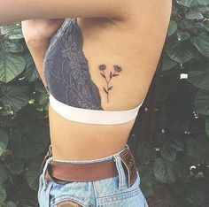 the back of a woman's stomach with a flower tattoo on her left side