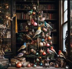 a christmas tree with ornaments and birds on it in front of a bookshelf