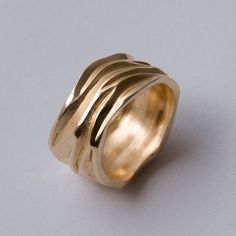 a gold ring is shown on a white surface, with the top part of it curled up