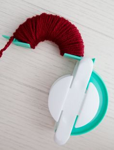 a red ball of yarn sitting on top of a white table next to a pair of scissors