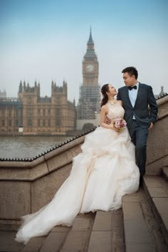 a bride and groom are standing on the steps in front of big ben