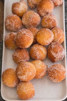 several sugared donuts are on a white platter