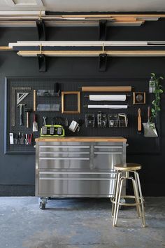 an industrial style kitchen with black walls and stainless steel appliances on the wall, along with two stools