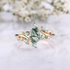 a green and white stone ring sitting on top of a table next to some flowers