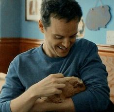 a man sitting at a table holding a piece of food in his hands and smiling