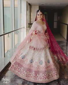 a woman in a pink and white bridal gown posing for the camera with her hand on her hip