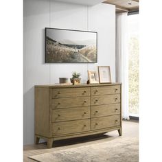 a wooden dresser sitting in front of a window next to a painting on the wall